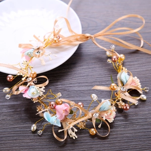 Handmade bridal flower crown with pink floral accents and pearls on a dark wood surface