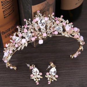 Elegante conjunto de tiara nupcial dorada con cristales rosas y pendientes sobre libros
