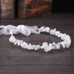 Détail d'un bandeau de mariée avec fleurs en tissu blanc, perles et cristaux sur fil
