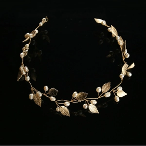 Handmade bridal headband with golden leaves and white pearls on reflective black surface