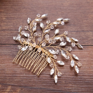 Handmade gold bridal hair comb with glass crystals and beads on a rustic wood background