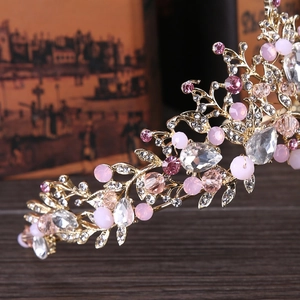 Detalle de corona nupcial dorada con cristales rosas e intrincado diseño de ramas florales