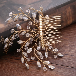 Handmade golden bridal hair comb with crystals and leaves on vintage book background