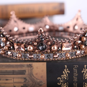 Macro detail of vintage baroque crown featuring black gemstones and faux pearls on books
