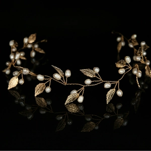 Elegant bridal vine headband with white pearls and gold metal leaves on a black background