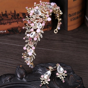 Detalle de corona de cristal rosa y pendientes con intrincados motivos de flores doradas