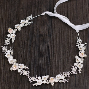Détail d'un accessoire de mariée avec fleurs en nacre et strass sur bois brun