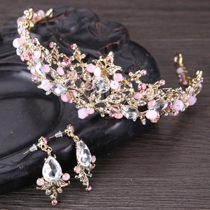Detalle de corona de novia de cristal rosa y pendientes en un plato vintage oscuro