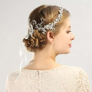 Eleganter Brauthaarschmuck mit Strassblumen und Perlen am Model mit Spitzen-Brautkleid