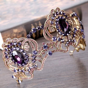 Vintage gold bridal crown with purple crystals and rhinestones on dark wood background