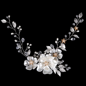 Dettaglio fascia da sposa con fiori bianchi, perle e foglie argentate su sfondo nero