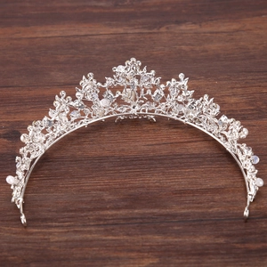 Detailed view of handmade silver bridal tiara with pearls and crystals on wooden surface