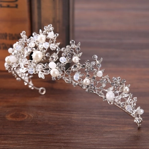 Silver bridal crown with white pearls and crystals on a rustic wooden background