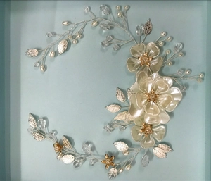 Dettaglio di un tralcio per capelli da sposa con fiori di raso e accenti di foglie argento