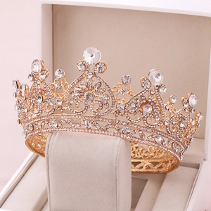 Detailed view of a gold bridal crown with crystals and heart patterns in a jewelry box