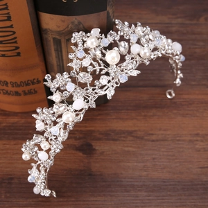 Silver bridal crown with pearls and crystals on vintage books and wooden surface