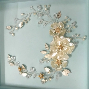 Dettaglio di un accessorio per capelli da sposa fatto a mano con perle e petali di seta