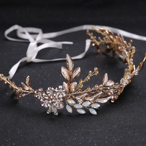 Détail d'un bandeau de mariée avec feuilles dorées, fleurs et rubans de satin blanc