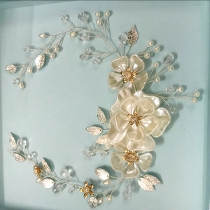 Dettaglio dell'accessorio da sposa fatto a mano con perle bianche e foglie d'argento