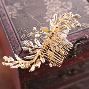 Detail view of a vintage golden leaf hair comb with pearls on a classic wooden box