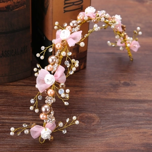 Dettaglio cerchietto floreale dorato fatto a mano con fiocco rosa, perle e cristalli