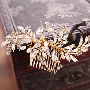 Elegant gold bridal hair comb with pearls and rhinestones resting on a vintage jewelry box