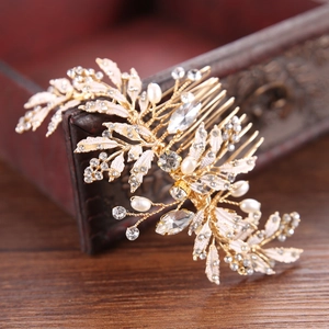 Detail of vintage gold bridal hair comb with pearls and rhinestones on a wooden box