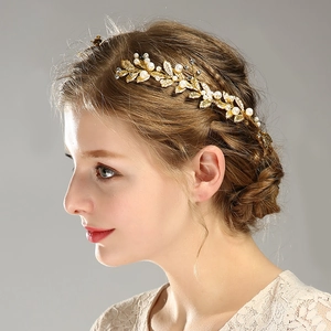 Détail d'un accessoire cheveux feuille dorée avec perles blanches et strass brillants