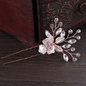 Macro shot of rose gold flower hair pin with sparkling rhinestones on vintage wood background
