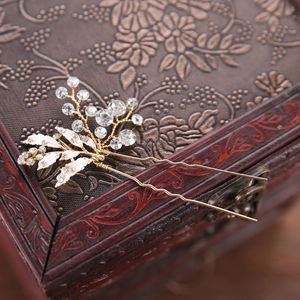 Close-up of golden bridal hair comb with sparkling rhinestones on vintage wooden box