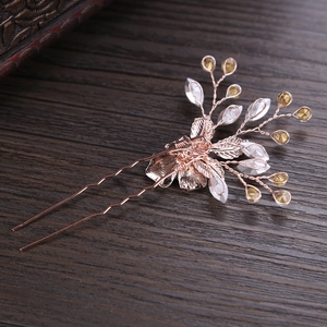 Rose gold U-shaped bridal hair pin with crystals and leaves on dark wood background