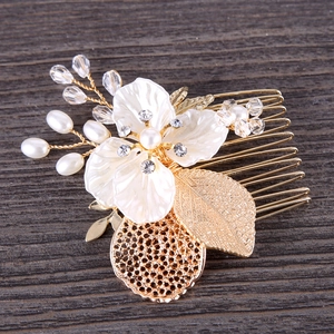 Golden leaf hair comb with pearls and crystals for bridal styling on wood background