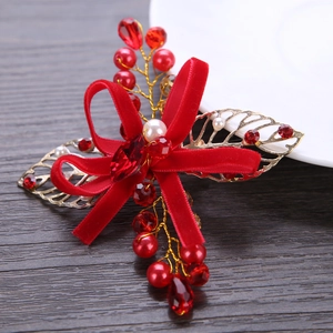 Detail of red velvet bow hair clip with gold metal leaves and sparkling crystals