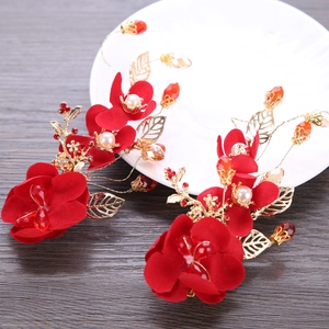 Detailed macro view of handmade red fabric flowers with pearls and gold metal leaves