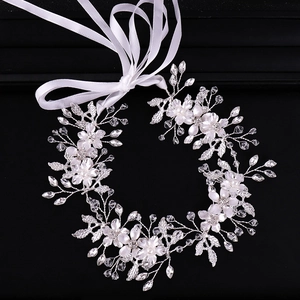Detail of handmade silver floral hairpiece with crystals and white satin ribbon