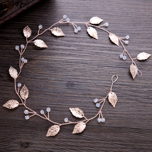 Rose gold leaf bridal headband with translucent beads on a vintage wood background