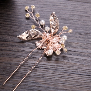Forcina sposa oro rosa con foglie di cristallo e perle finte su sfondo di legno scuro