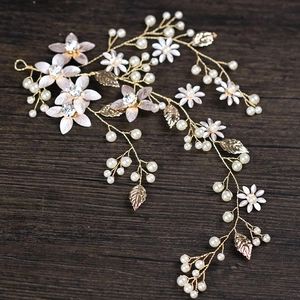 Elegant gold leaf bridal hair vine with white pearls and flowers on dark wood background