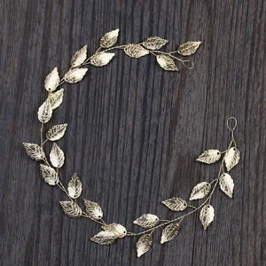 Detail of elegant gold leaf bridal hair vine with fine textures on dark wood background