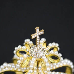 Macro shot of golden bridal crown featuring a diamond-encrusted cross and pearls
