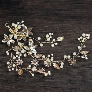Golden bridal hair vine with white pearls and leaves on a vintage wood background