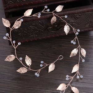 Close-up of rose gold leaf bridal headband with crystal beads on wooden background