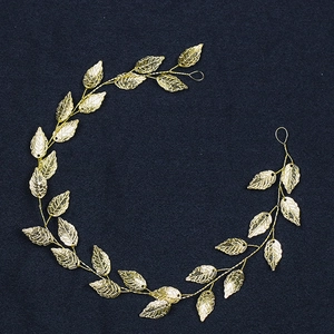 Detail of golden leaf bridal hairpiece with intricate vein texture on blue fabric