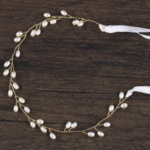Bijou de tête de mariée doré élégant avec perles blanches et ruban sur bois sombre