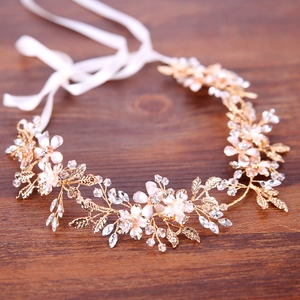 Golden bridal headband with pink flowers, pearls and crystals on rustic wood background