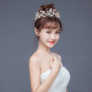 Détail d'une couronne de mariée dorée avec perles et papillons portée par un mannequin