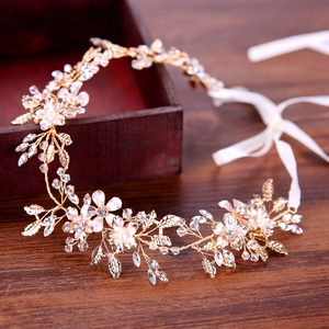 Elegant gold bridal headband with pink flowers and crystals on a rustic wooden surface