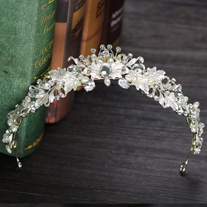 Elegant gold bridal crown with crystals and pearls on vintage books background