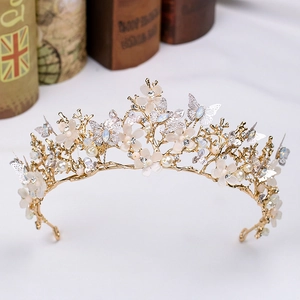 Détail d'un diadème de mariée doré avec fleurs mates, papillons en cristal et perles