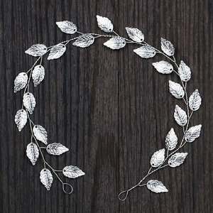 Detailed view of silver metal leaf headband with intricate texture on dark wooden surface